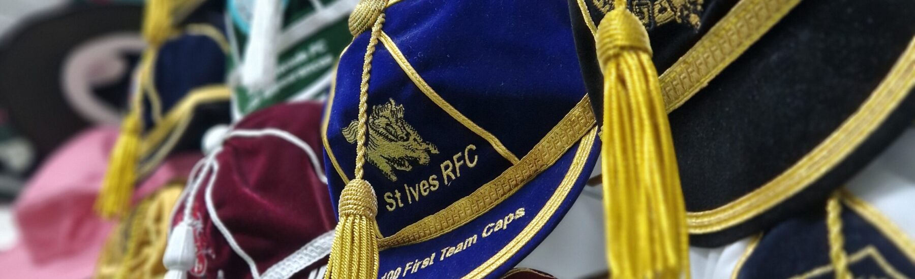 Honour Cap with tassles hanging off the wall with different embroidery and logos.