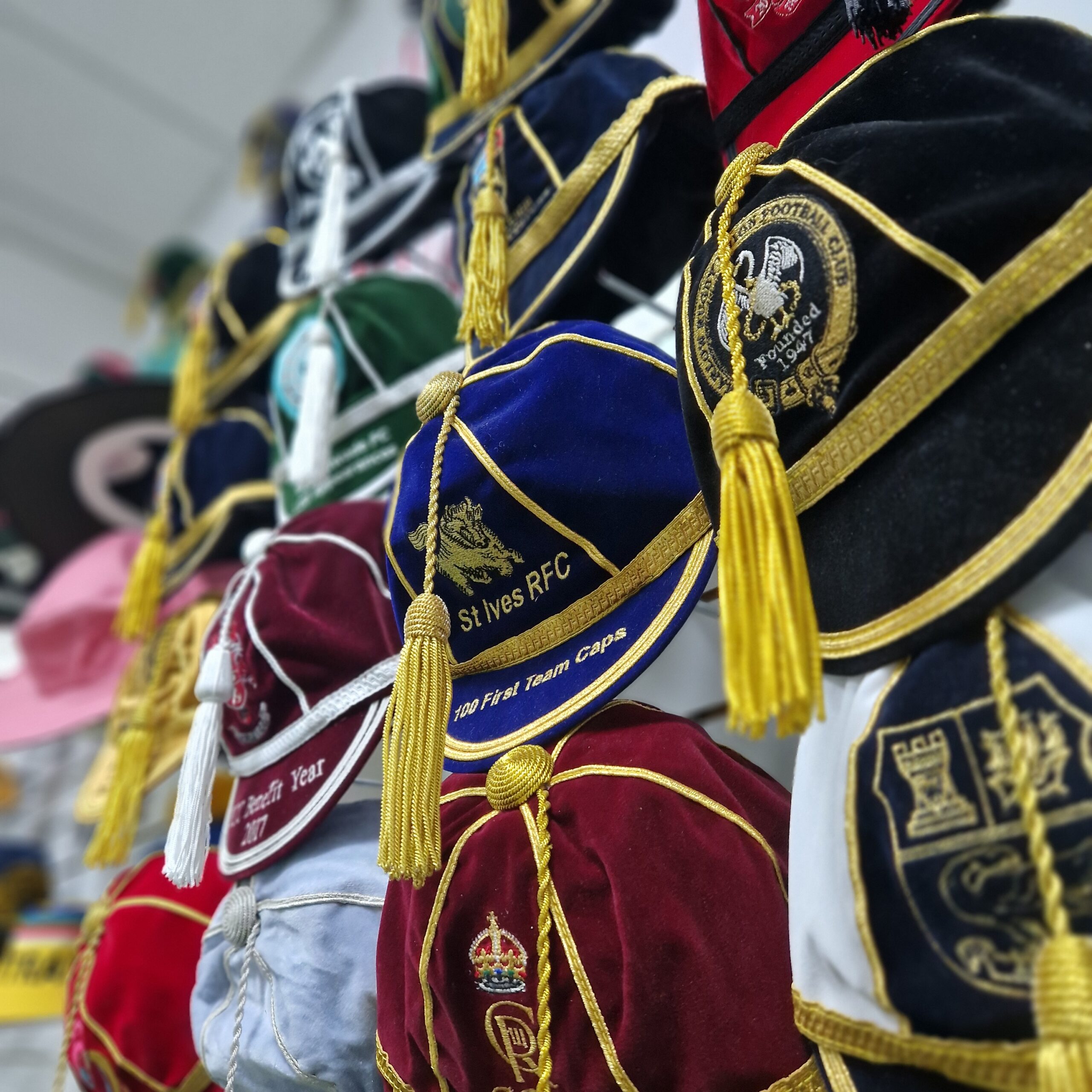 Honour Cap with tassles hanging off the wall with different embroidery and logos.