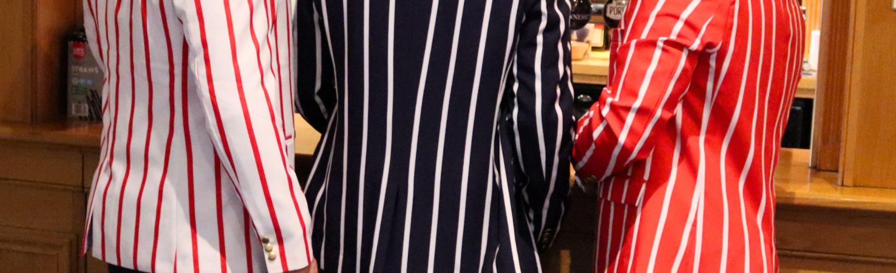 three men at a bar wearing striped blazers