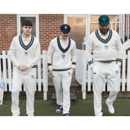 Team wearing traditional cricket jumpers outside a pavilion